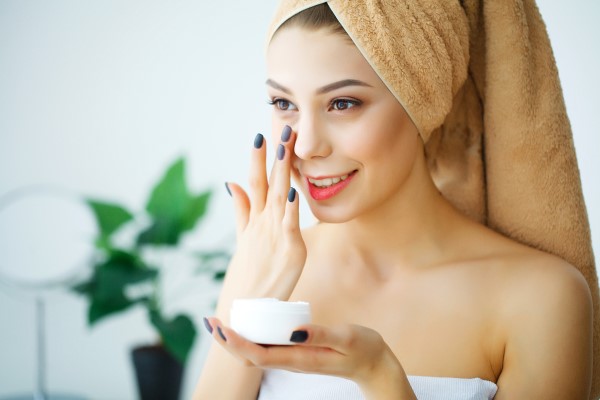 young woman applying moisturizer
